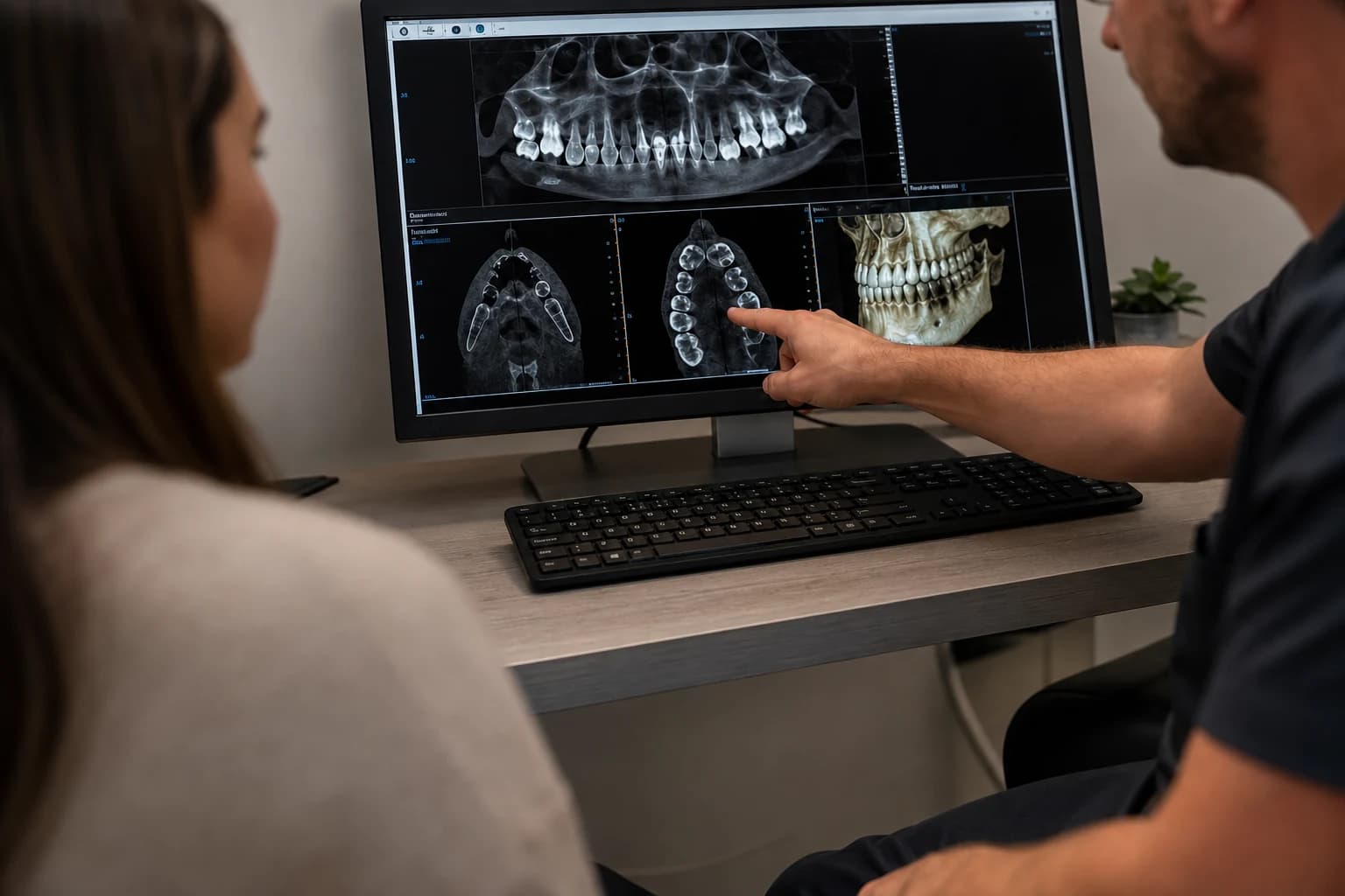 Lekarz omawia z pacjentem obraz tomografii komputerowej szczęki na monitorze